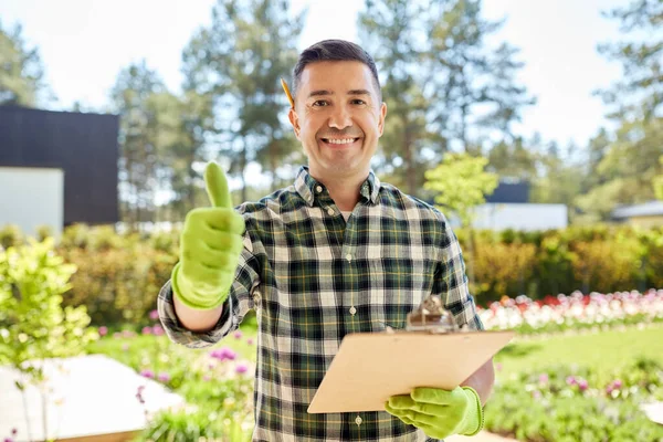 Чоловік з буфетом, що показує великі пальці в саду — стокове фото