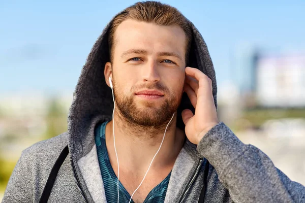 Homme dans les écouteurs écouter de la musique à l'extérieur — Photo