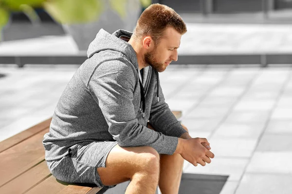 Young man sitting on bench outdoors — Stock Photo, Image