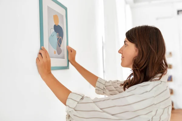 woman decorating home with picture in frame