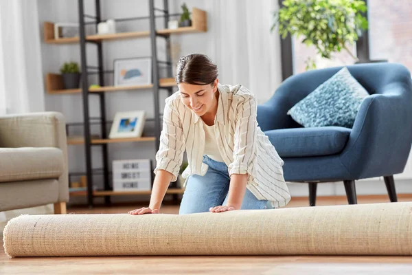 Jeune femme déroulant tapis à la maison — Photo