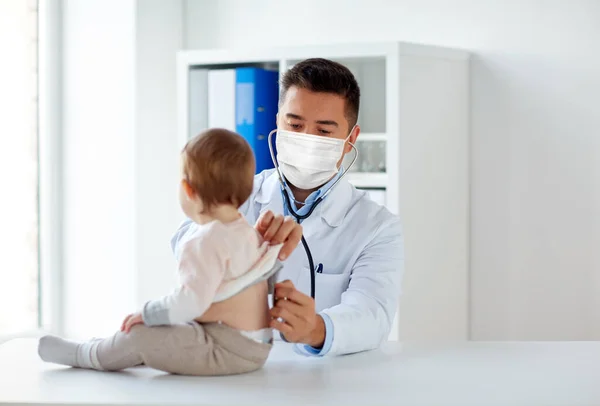 Médico em máscara com estetoscópio e bebê na clínica — Fotografia de Stock