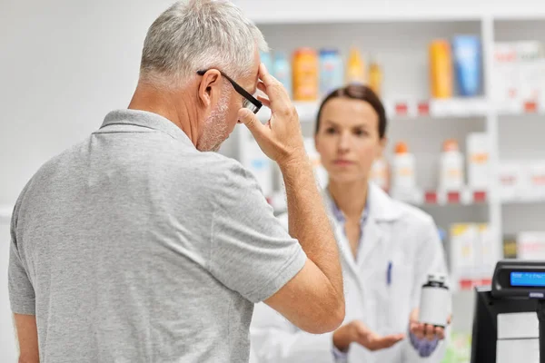 Farmacéutico y hombre viejo con la medicina en la farmacia —  Fotos de Stock