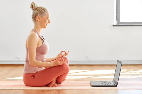 Donna con computer portatile in posa loto allo studio di yoga — Foto Stock