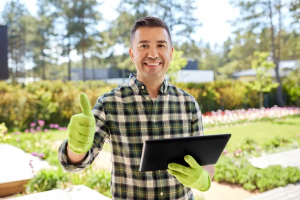 Mężczyzna z tabletem pokazujący kciuki do góry w ogrodzie — Zdjęcie stockowe
