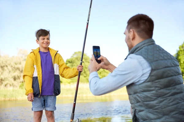 Baba oğlunu nehirde oltayla fotoğraflıyor. — Stok fotoğraf