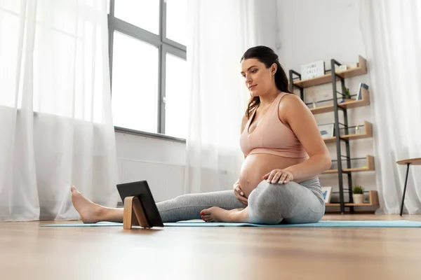 Femme enceinte avec tablette pc faire du sport à la maison — Photo