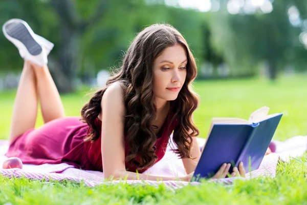 夏の公園で本を読んでいる幸せな若い女性 — ストック写真