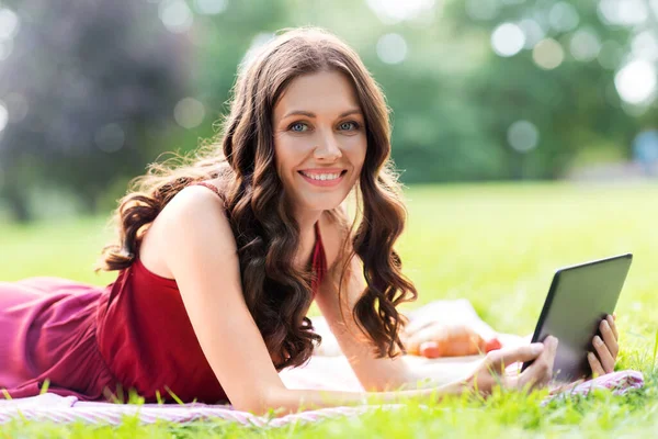 Mujer feliz con la tableta en el picnic en el parque —  Fotos de Stock