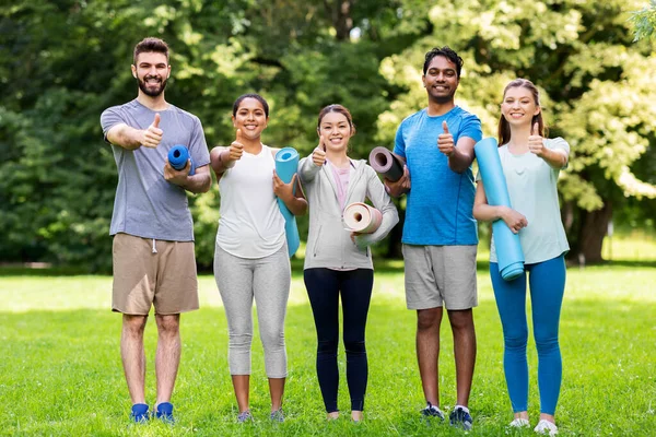 People with yoga mats showing thumbs up at park — Stock Photo, Image