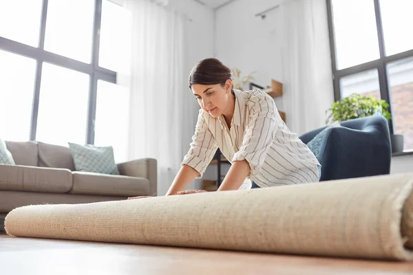 Jeune femme déroulant tapis à la maison — Photo