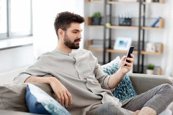 Jeune homme avec smartphone à la maison — Photo