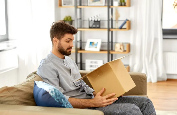 Hombre decepcionado abriendo la caja de paquetes en casa — Foto de Stock