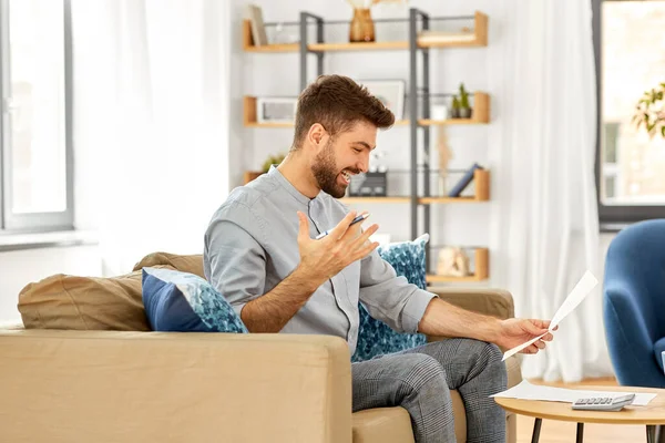 Mann mit Rechnungen rechnet zu Hause mit Taschenrechner — Stockfoto