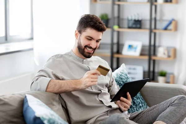 Homem com tablet computador e cartão de crédito em casa Fotos De Bancos De Imagens