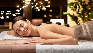 smiling woman having hot stone massage at spa clipart