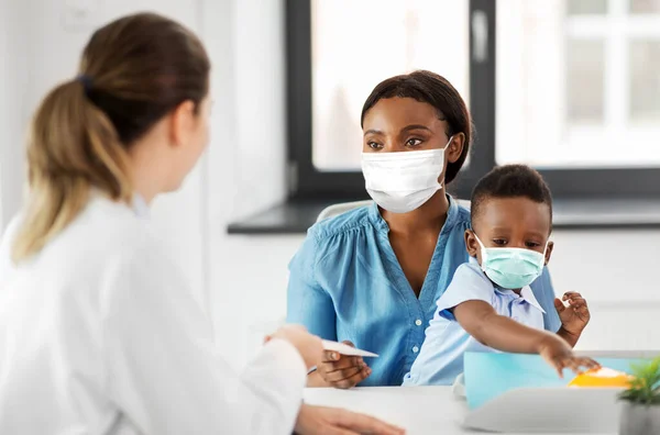 Mãe com filho bebê em máscaras e médico na clínica — Fotografia de Stock