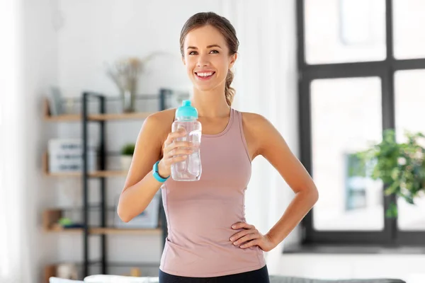 Lächelnde junge Frau mit Flasche Wasser zu Hause — Stockfoto