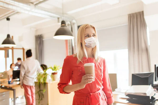 Ufficio femminile in maschera con tazza di caffè — Foto Stock