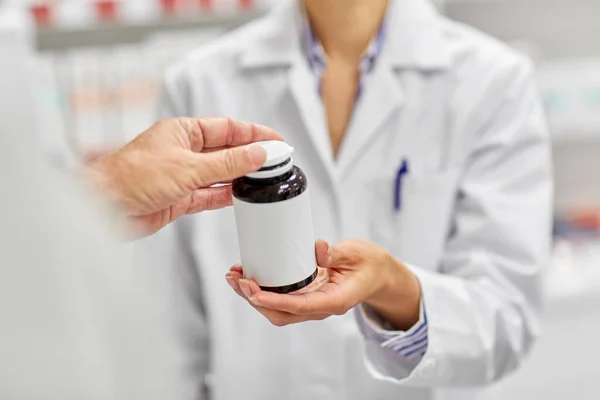 Farmacéutico y cliente con medicamentos en la farmacia —  Fotos de Stock