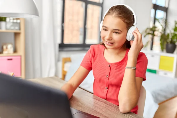 Menina em fones de ouvido com computador portátil em casa — Fotografia de Stock