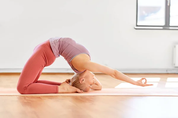 Joven mujer haciendo rey paloma pose en yoga estudio —  Fotos de Stock