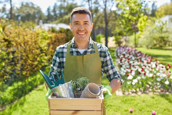 happy man with tools in box at summer garden