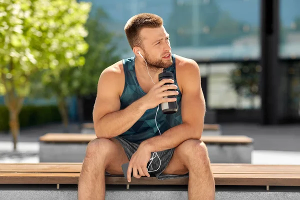 Sportsman with earphones and bottle in city — Stock Photo, Image