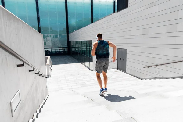 Young man in headphones running downstairs — Stock Photo, Image