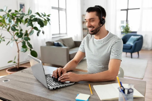 Hombre con auriculares y portátil trabajando en casa —  Fotos de Stock