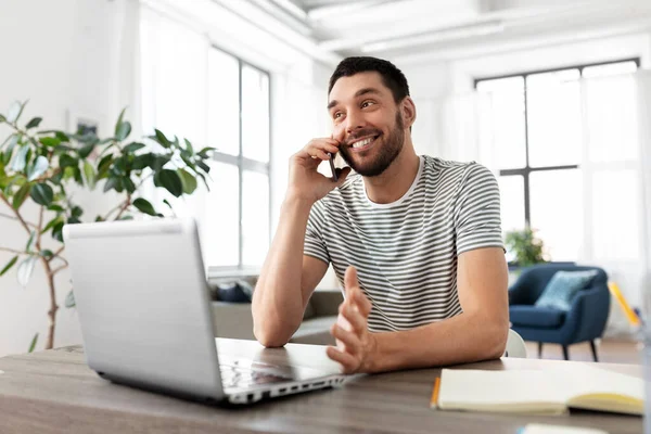 Man med laptop ringer på telefon på hemmakontoret — Stockfoto