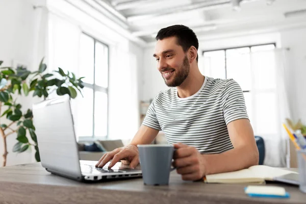 Man med bärbar dator dricka kaffe på hemmakontoret — Stockfoto