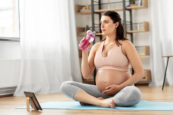 Femme enceinte boire de l'eau après le yoga à la maison — Photo