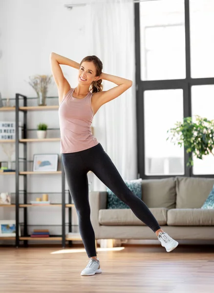 Smiling young woman exercising at home — Stock Photo, Image