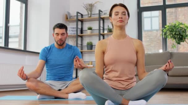 Couple méditant dans la pose de lotus yoga à la maison — Video
