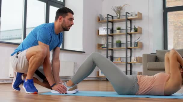 Kvinna med personlig tränare gör sit ups hemma — Stockvideo