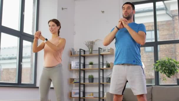 Feliz pareja haciendo ejercicio y haciendo sentadillas en casa — Vídeos de Stock