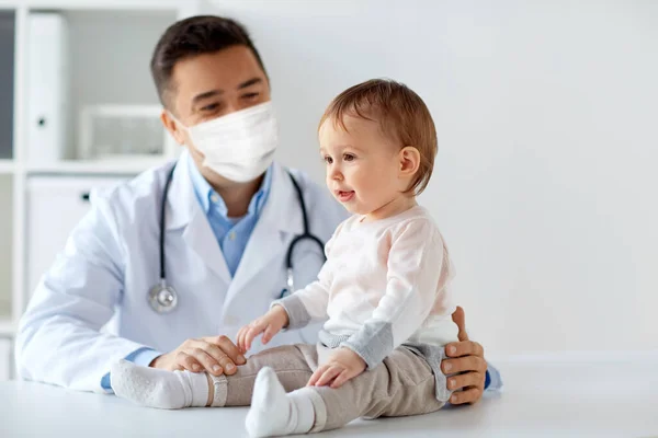 Médico ou pediatra em máscara com bebê na clínica — Fotografia de Stock