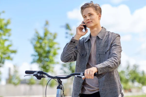 Młody człowiek z rowerem dzwoni przez telefon w mieście — Zdjęcie stockowe