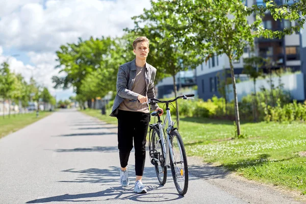 Junger Mann mit Fahrrad läuft Stadtstraße entlang — Stockfoto