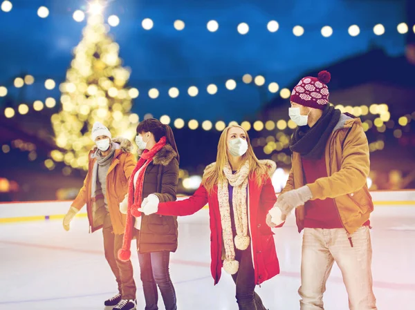 Vrienden in maskers op kerst schaatsbaan — Stockfoto