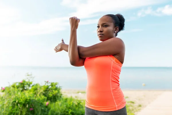 Young african american woman stretching on beach — Stock Photo, Image