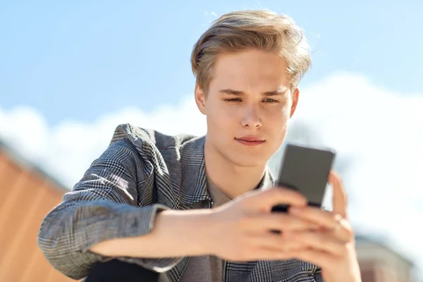 Ung man eller tonåring pojke med hjälp av smartphone utomhus — Stockfoto