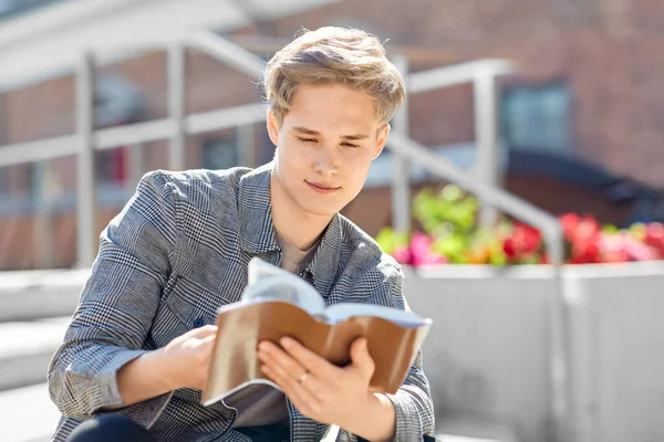 Jonge man of tiener jongen lezen boek in de stad — Stockfoto