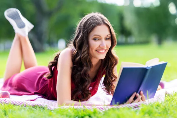 Šťastná usměvavá žena čtení knihy v letním parku — Stock fotografie