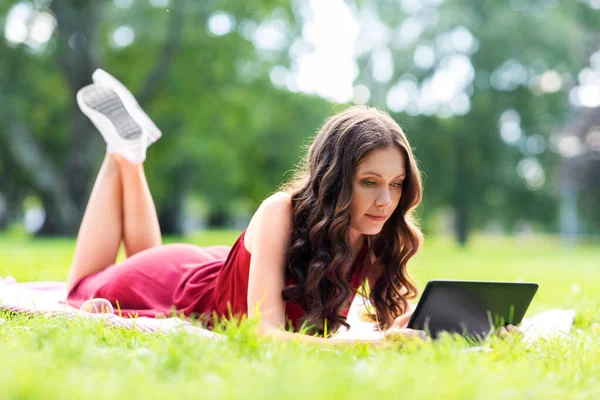 Mujer feliz con la tableta en el parque —  Fotos de Stock