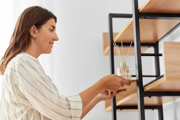 Woman placing aroma reed diffuser to shelf home — Stock Photo, Image