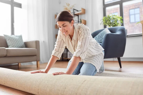 Jeune femme déroulant tapis à la maison — Photo