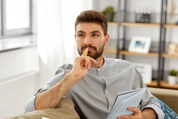 Hombre escribiendo a cuaderno y pensando en casa — Foto de Stock