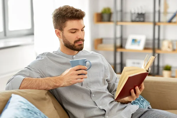 Hombre leyendo libro y bebiendo café en casa — Foto de Stock